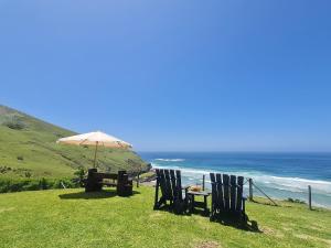 two chairs and an umbrella next to the ocean at BLACK ROCK ACCOMMODATION in Hole in the Wall