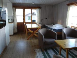 ein Wohnzimmer mit einem Tisch, Stühlen und einem Bett in der Unterkunft Fyrklöverns Stugby in Rättvik