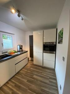 cocina con electrodomésticos blancos y suelo de madera en FH Ausblick en Waldkirchen