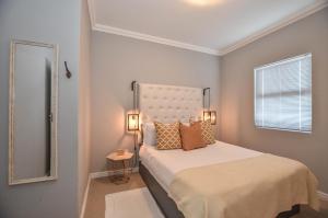 a small bedroom with a bed and a mirror at Apartment 6 in Yzerfontein