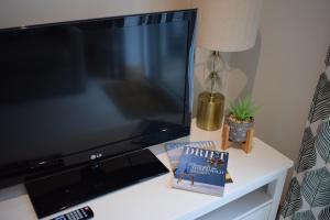a tv on a table with a book and a lamp at The Little House, Wadebridge, Cornwall in Wadebridge