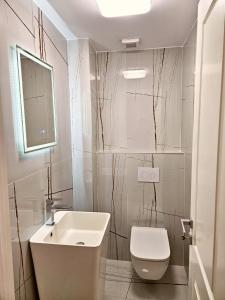 a white bathroom with a sink and a toilet at Luxury Apartment in Bucharest