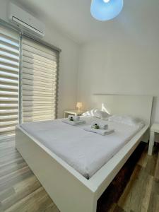 ein weißes Schlafzimmer mit einem großen weißen Bett mit zwei Kerzen darauf in der Unterkunft Sandy Beach Complex in Perivolia