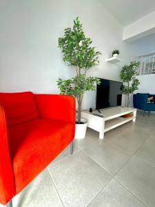 ein Wohnzimmer mit einem roten Sofa und zwei Topfbäumen in der Unterkunft Sandy Beach Complex in Perivolia