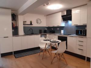 a kitchen with white cabinets and a table and chairs at No's 2 and 5 Llewelyn Apartments in Llanberis