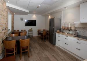 a kitchen with a refrigerator and a table with chairs at Hotell Havsporten in Karlholmsbruk