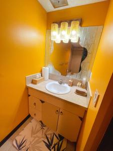 a yellow bathroom with a sink and a mirror at Lu Yao Inn in Calgary