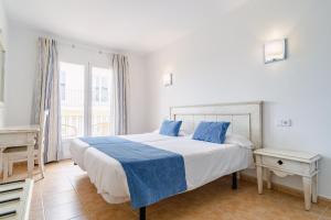 a bedroom with a large white bed with blue pillows at Hostal HPC Porto Colom in Portocolom