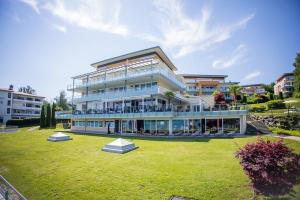 un grand bâtiment avec une pelouse devant lui dans l'établissement Seehotel Süd, à Velden am Wörther See