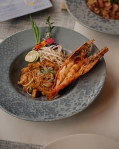 a plate of food with shrimp and noodles on a table at Homm Sukhumvit34 Bangkok - a brand of Banyan Group in Bangkok