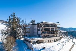 アヴェレンゴにあるApartment Hotel Christineの雪中の大きな木々の建物