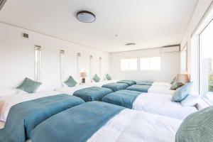 a room with a row of beds with blue pillows at 南紀白浜ビューポイント in Shirahama