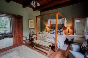 a bedroom with a canopy bed and a living room at Moolmanshof 1798, Traditional Cape Dutch H-Shaped Farmhouse in Swellendam