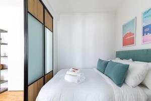 Un dormitorio con una gran cama blanca con toques azules en Montaigne/Place de l’Alma : Beautiful Apartment 4P, en París