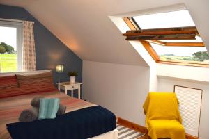 a bedroom with a bed and a yellow chair at The Little House, Wadebridge, Cornwall in Wadebridge