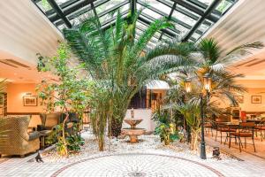 un salón acristalado con palmeras, mesas y sillas en Villa Beaumarchais en París