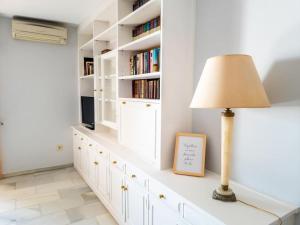 ein weißes Zimmer mit einer Lampe und Bücherregalen in der Unterkunft Gran apartamento primera línea in Estepona