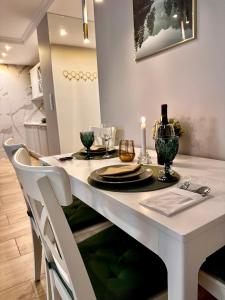 uma mesa de jantar com uma tampa de mesa branca com pratos e velas em Apartamenty Kielce- GREEN FOREST APARTAMENT, faktura, parking, centrum em Kielce