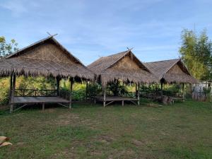 a group of three huts with benches in the grass at ลาน​กางเต๊นท์​ข้าวซอย​เขาค้อ​ in Ban Khao Ya Nua