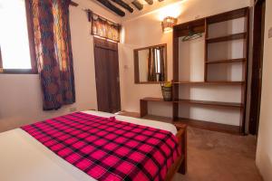 a bedroom with a bed with a plaid blanket on it at The Wishing Tree in Pingwe