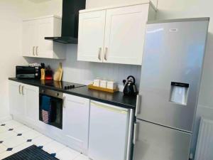 a kitchen with white cabinets and a stainless steel refrigerator at 7 Bedroom House in Town Centre near Beach - Sleeps 13 in Hastings