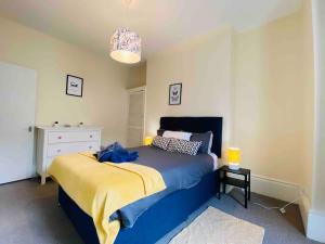 a bedroom with a bed with a blue and yellow blanket at 7 Bedroom House in Town Centre near Beach - Sleeps 13 in Hastings