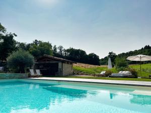 uma piscina com uma casa e um guarda-chuva em Barbarens Maison d'hotes em Castelnau-Barbarens