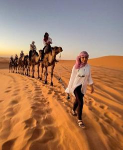 a group of people riding on camels in the desert at Bivouac Camel Trips in Merzouga