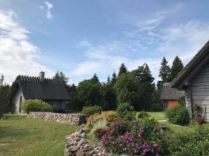 a yard with two houses and a stone wall at Romantiline saunamaja Pädaste lahe ääres in Pädaste