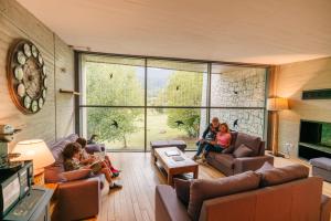 a group of people sitting in a living room with a large window at MónNatura Pirineus - AJOOO385 in Esterri d'Àneu