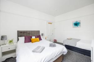 een slaapkamer met 2 bedden met witte en paarse kussens bij City Centre - Bright spacious Apartment - Short & Long stays Everhome by Luxiety Stays in Southend-on-Sea
