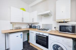 a kitchen with white cabinets and a washer and dryer at City Centre - Bright spacious Apartment - Short & Long stays Everhome by Luxiety Stays in Southend-on-Sea