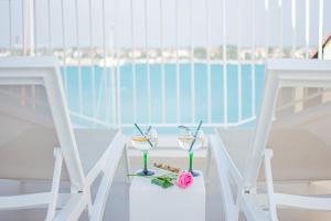 two glasses of wine sitting on a table with two chairs at Apartment seafront Umag center old town seaview 4 in Umag