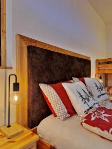 a bed with a wooden headboard with red and white pillows at B&B Ai Larici in Bocenago