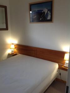 um quarto com uma cama branca com duas luzes em Superb well-equipped apartment em Le Dévoluy