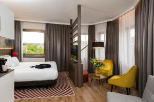 a hotel room with a bed and a yellow chair at NYX Hotel Bilbao by Leonardo Hotels in Bilbao