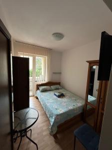 Schlafzimmer mit einem Bett, einem Tisch und einem Fenster in der Unterkunft Casa Rosa in Băile Olăneşti