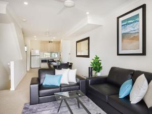 - un salon avec un canapé noir et des oreillers bleus dans l'établissement Emerald lakes 3 level villa, à Gold Coast