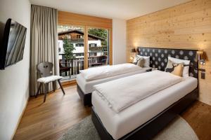 a hotel room with two beds and a balcony at Chalet Piz Buin in Klosters