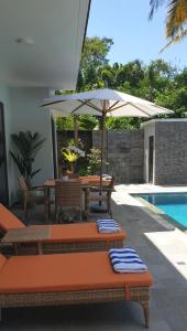 a patio with a table and umbrella next to a pool at Graha Ayoe in Sidemen