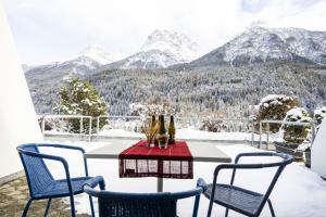 a table and chairs on a balcony with snow covered mountains at Chasa Tulai F83 in Scuol