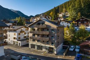 ein Apartmenthaus in den Bergen mit Autos auf einem Parkplatz in der Unterkunft Chalet Piz Buin in Klosters