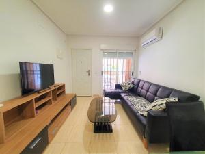een woonkamer met een zwarte leren bank en een flatscreen-tv bij Costa Azahar Bajo Nº 1009 in Oropesa del Mar