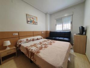 een slaapkamer met een bed en een bank bij Costa Azahar Bajo Nº 1009 in Oropesa del Mar