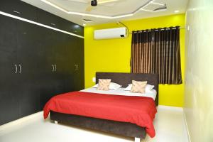 a bedroom with a bed with a red blanket and yellow walls at Srivari Homestay in Tirupati