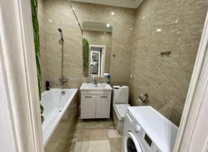 y baño con bañera, lavamanos, aseo y bañera. en Приятные апартаменты в элитном комплексе, en Almaty