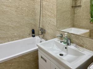 y baño con lavabo blanco y bañera. en Приятные апартаменты в элитном комплексе, en Almaty