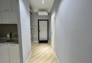 Una cocina con gabinetes blancos y un pasillo con puerta. en Приятные апартаменты в элитном комплексе, en Almaty