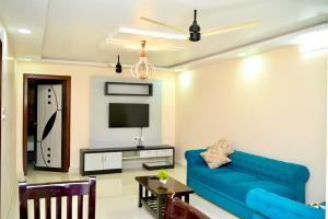 a living room with a blue couch and a tv at Srivari Homestay in Tirupati