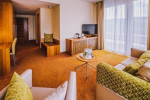 a living room with couches and a table and a television at Seehotel Süd in Velden am Wörthersee